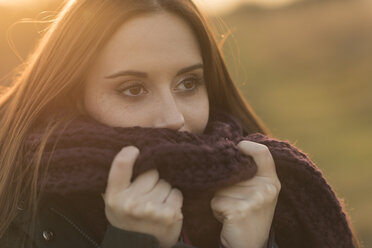 Young woman in rural setting, wearing knitted scarf - CUF16314