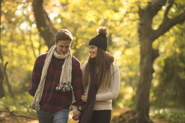 Junges Paar geht durch den Wald, hält sich an den Händen und lächelt - CUF16323