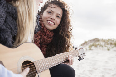 Two young female friends playing guitar at beach, Western Cape, South Africa - CUF16355