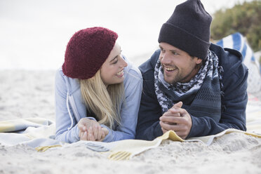 Junges Paar liegt auf einer Picknickdecke und unterhält sich am Strand, Westkap, Südafrika - CUF16376