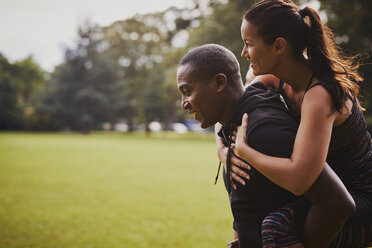 Man and woman having fun training in park, giving piggy back - CUF16386