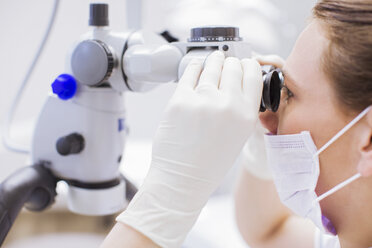 Side view of dentist looking through microscope - CUF16404