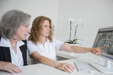 Ältere Frau zeigt älteren Frau Röntgenbild auf Computerbildschirm zeigen - CUF16409
