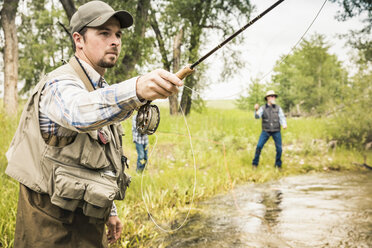 Man fly fishing with family in river - CUF16442