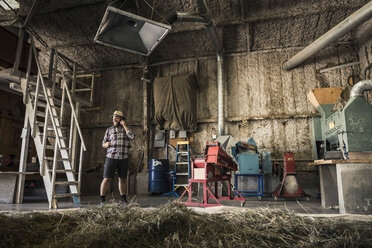 Scientist talking on smartphone in plant growth research facility barn - CUF16467