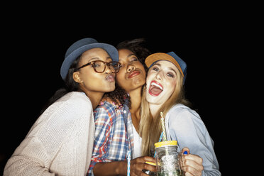Junge Frauen, die zusammengekauert Einmachgläser halten und mit gespitzten Lippen in die Kamera schauen - CUF16504