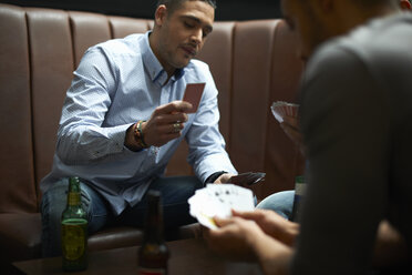 Three male friends playing card game in traditional UK pub - CUF16685