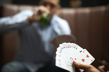 Male hand playing cards in traditional UK pub - CUF16689