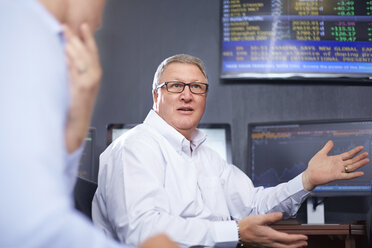 Reifer Geschäftsmann mit Brille im Büro im Gespräch mit Kollegen, Handgesten - CUF16745