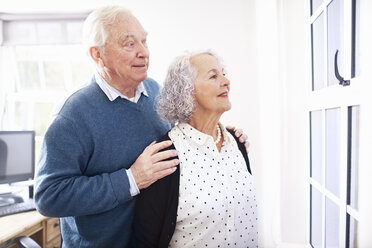 Senior couple in office looking out of window smiling - CUF16749