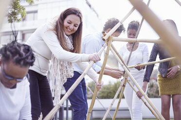 Colleagues in team building task building wooden structure smiling - CUF16763