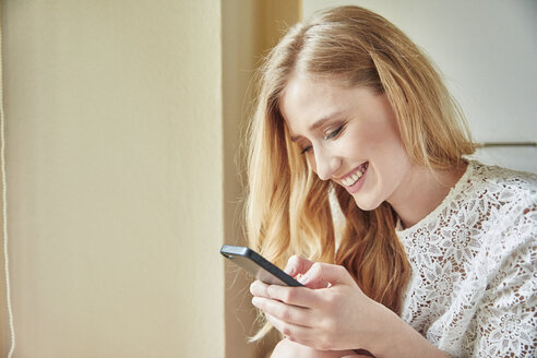 Junge Frau liest zu Hause einen Smartphone-Text - CUF16833