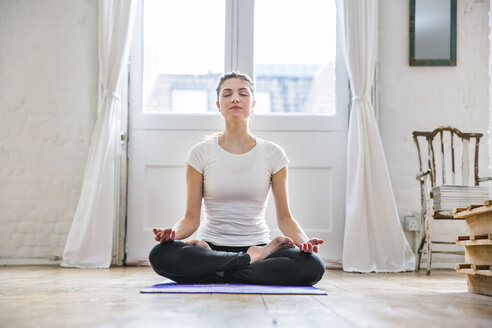 Junge Frau übt Yoga Lotussitz in der Wohnung - CUF16862