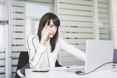 Businesswoman at office desk staring at laptop - CUF16888