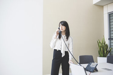 Young businesswoman talking on landline in office - CUF16893