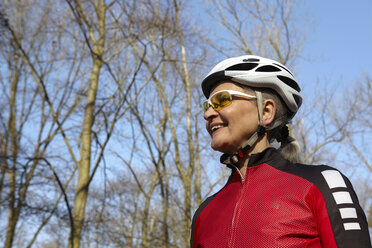 Niedriger Blickwinkel auf eine Frau mit Fahrradhelm und Sonnenbrille, die lächelnd wegschaut - CUF17047