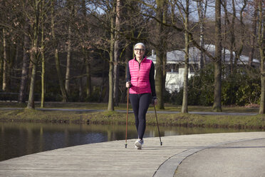 Vorderansicht einer Frau beim Nordic Walking am Teich in voller Länge - CUF17051