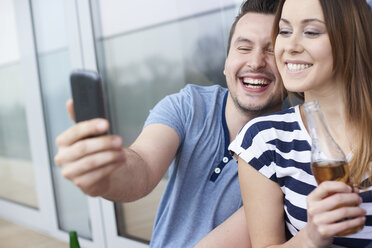 Junges Paar, das im Freien sitzt und ein Selbstporträt mit einem Smartphone aufnimmt - CUF17067