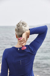 Ältere Frau am Meer, die mit Handgewichten trainiert, Rückansicht - CUF17133