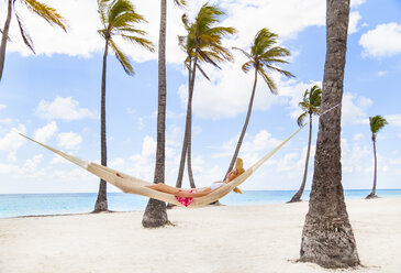 Young woman reclining in palm tree hammock at beach, Dominican Republic, The Caribbean - CUF17201