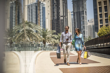 Touristenpaar schlendert mit Einkaufstüten auf einem Gehweg, Dubai, Vereinigte Arabische Emirate - CUF17220