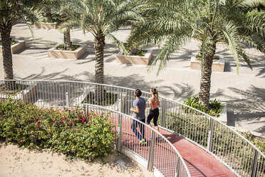 Hoher Blickwinkel auf ein laufendes Paar, das eine Fußgängerbrücke hinunterläuft, Dubai, Vereinigte Arabische Emirate - CUF17227