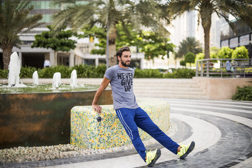 Mann trainiert, macht Aufwärmübungen im Park, Dubai, Vereinigte Arabische Emirate - CUF17229