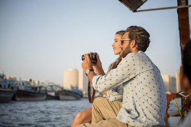 Romantic couple reviewing camera on boat at Dubai marina, United Arab Emirates - CUF17233