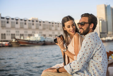 Romantisches Paar beim Fotografieren auf einem Boot im Jachthafen von Dubai, Vereinigte Arabische Emirate - CUF17235