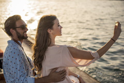 Romantisches Paar macht Smartphone-Selfie auf einem Boot im Jachthafen von Dubai, Vereinigte Arabische Emirate, lizenzfreies Stockfoto