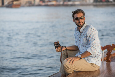 Young man looking back from boat at Dubai marina, United Arab Emirates - CUF17240