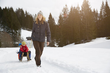 Frau zieht Söhne auf Schlitten in verschneiter Landschaft, Elmau, Bayern, Deutschland - CUF17259