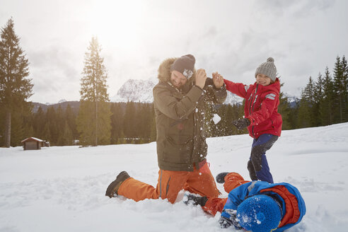 Mann und Söhne bei einer Schneeballschlacht im Winter, Elmau, Bayern, Deutschland - CUF17263