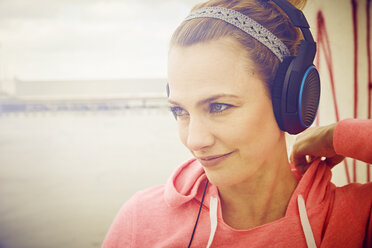 Mid adult woman listening to headphone music on rooftop parking lot - CUF17276