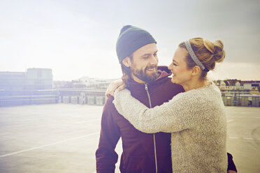 Mid adult woman hugging boyfriend on rooftop parking lot - CUF17279