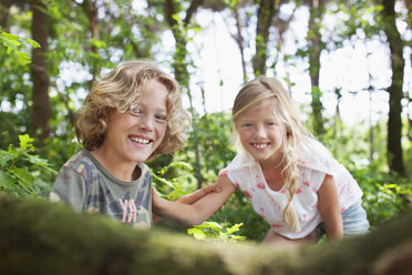 Junge und Mädchen im Wald schauen lächelnd in die Kamera - CUF17294