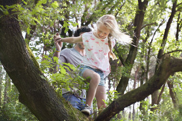 Vater hilft Tochter beim Klettern auf den Baum - CUF17295