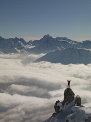 Feiernder Bergsteiger auf dem aus dem Nebel auftauchenden Gipfel, Bettmeralp, Wallis, Schweiz - CUF17328