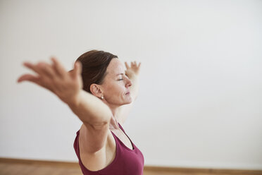 Seitenansicht einer Frau im Fitnessstudio, Arm angehoben, Augen in Yogastellung geschlossen - CUF17368