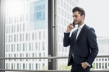 Geschäftsmann am Fenster mit Mobiltelefon - DIGF04514