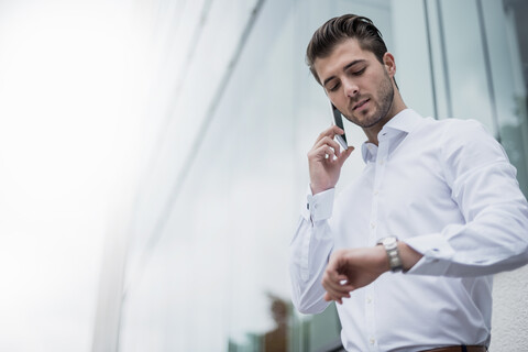 Geschäftsmann mit Mobiltelefon, der die Zeit überprüft, lizenzfreies Stockfoto