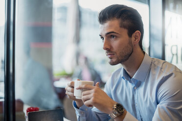 Young businessman drinking coffee in a cafe - DIGF04542