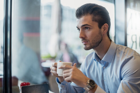 Junger Geschäftsmann trinkt Kaffee in einem Café - DIGF04542