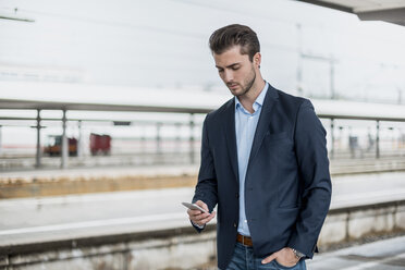 Businessman using cell phone at the platform - DIGF04546