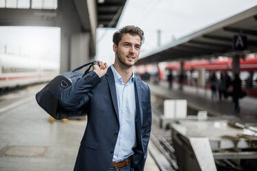 Smiling businessman with bag at the platform - DIGF04548