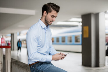 Businessman using cell phone at the station - DIGF04552