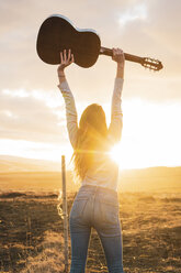 Iceland, woman with guitar at sunset - KKAF01098