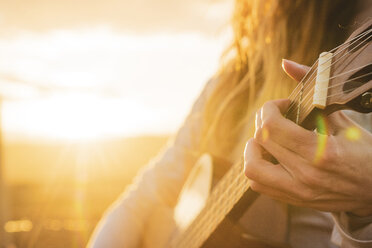 Island, Frau spielt Gitarre bei Sonnenuntergang - KKAF01100