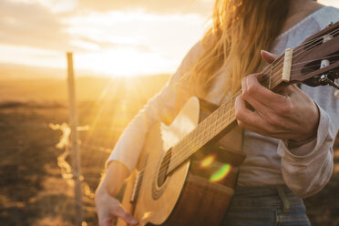 Island, Frau spielt Gitarre bei Sonnenuntergang - KKAF01101