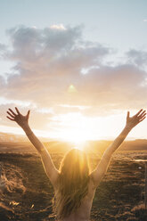 Iceland, young woman with raised arms at sunset - KKAF01107